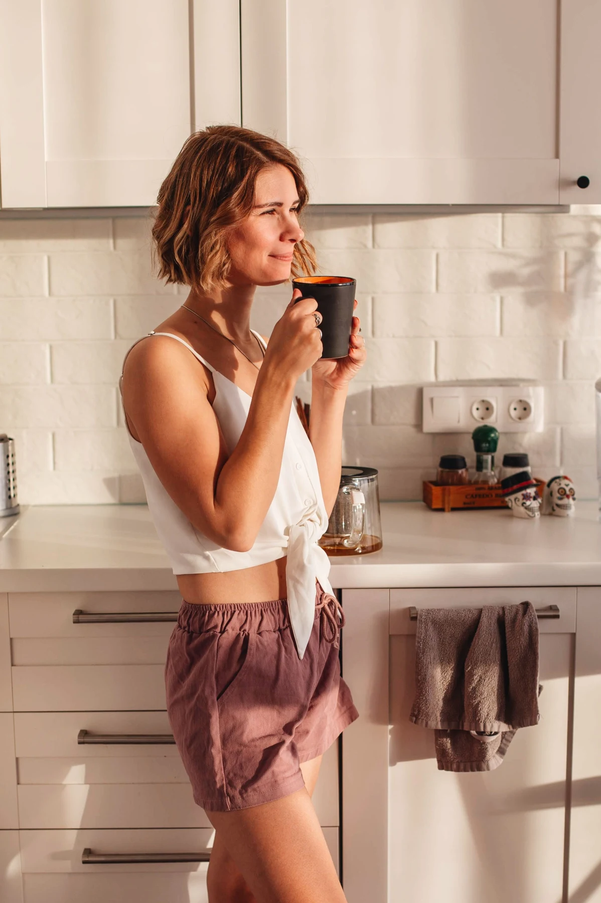Vrouw geniet van een kop koffie in een zonnige keuken
